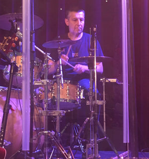 Man playing drums behind a glass屏障